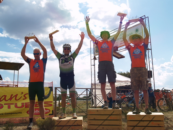 matt berrault of bicycle world tv on the podium surrounded by absolute bike team members during the white mountains race
